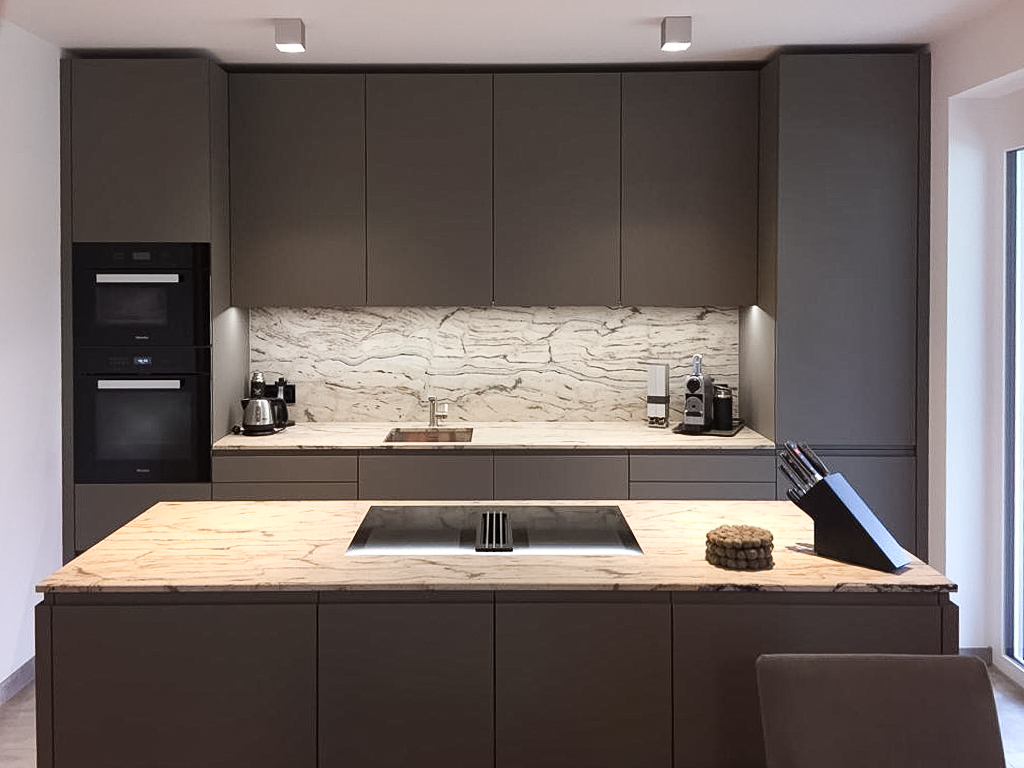 Moderne Küche mit einem großen Kücheninsel, hochwertigen Geräten und elegantem Marmorarbeitsplatz.